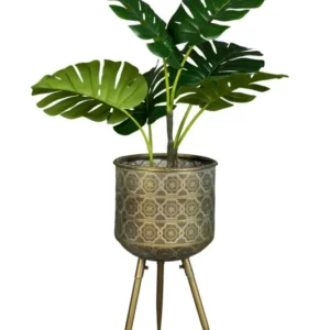 Blumenständer BOTANIQUE L mit gemustertem Metallbehälter auf drei Beinen, gefüllt mit grüner Pflanze.