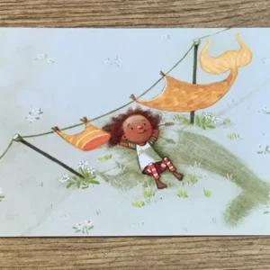 Postkarte: Kind liegt unter einer Wäscheleine mit Nixenkostüm und schaut in den Himmel