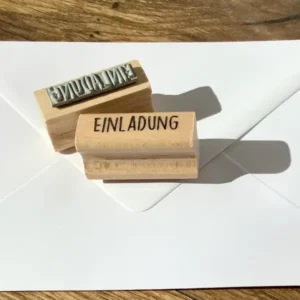 Länglicher Holzstempel mit dem Stempeltext EINLADUNG in Großbuchstaben.