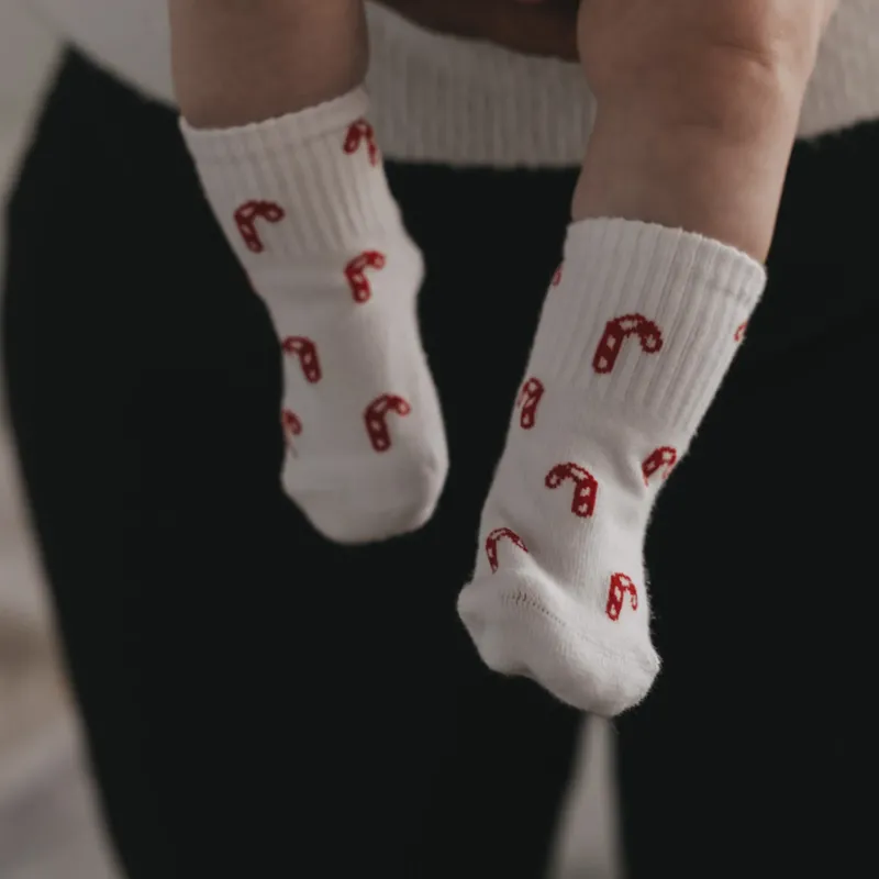 Baby trägt weiße Socken mit roten Zuckerstangen, Detailaufnahme der Füße