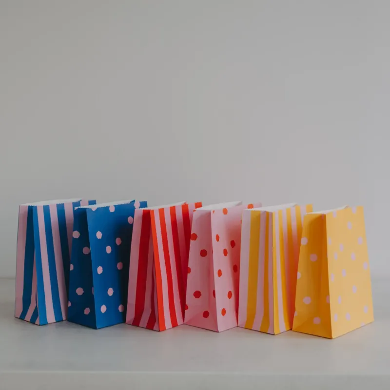 Verschiedene bunte Papier-Geschenktüten nebeneinander, moderne Designs mit Streifen und Punkten