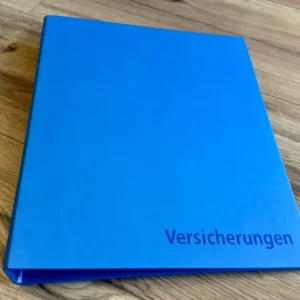 Blauer Ordner mit der Aufschrift "Versicherungen"